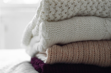 Fototapeta na wymiar Warm sweaters. Pile of knitted clothes on warm background, sweaters, knitwear, space for text, Autumn winter concept. Copy Space