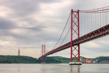 Fototapeta na wymiar The 25 April bridge (Ponte 25 de Abril) at cloudy day, Lisbon, Portugal.