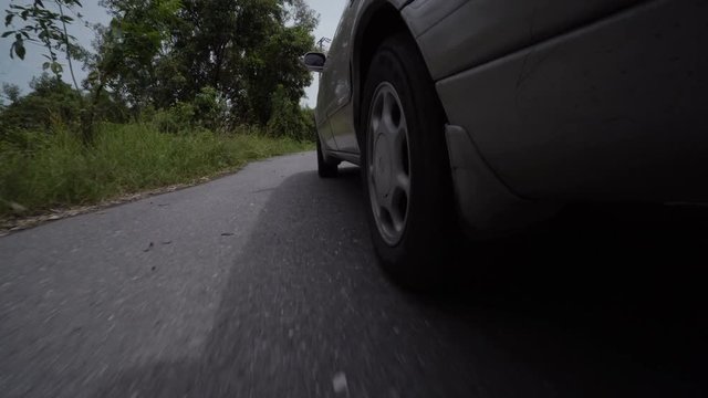 Driving a car on a country road. Wheels spinning POV. View from under the car
