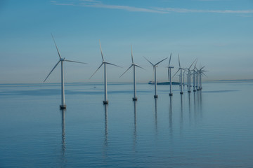 offshore windmill park alternative energy. windmills in the sea with reflection in the morning, denmark
