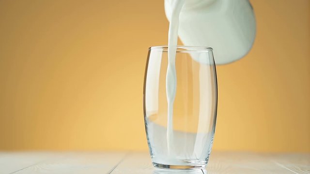 Pouring milk from a jug into a glass, slow motion.