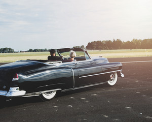 Couple driving classic car in summer time