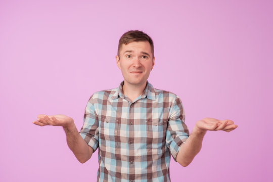Studio portrait of confused handsome guy showing I have no idea gesture.