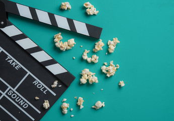 Movie clapper board with popcorn on blue background,top view