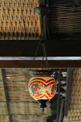 Traditional colorful Turkish mosaic lamp hanging on roof structure.