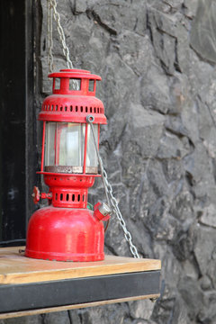 Red vintage kerosene oil lamp on wooden counter.