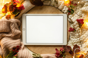 The tablet with red leaves and a dais on the wooden background. Concept of the autumn. View from...