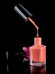 Nail polish dripping from brush into bottle isolated on black background