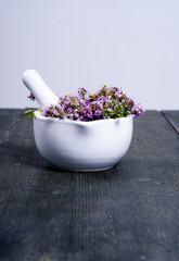 thyme flowers in a mortar on dark wood table