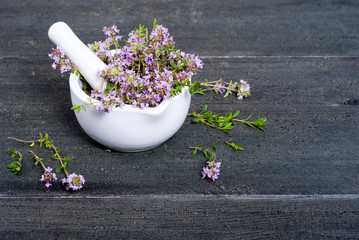 thyme flowers in a mortar on dark wood table