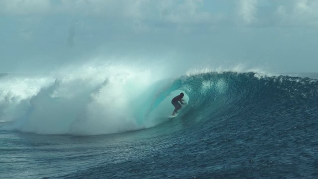 SLOW MOTION Wild emerald water splashes over surfer's head riding a breathtaking barrel wave during his fun summer vacation in French Polynesia. Epic shot of extreme sportsman surfboarding ocean waves