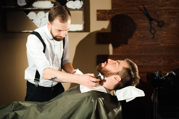 Master cuts hair and beard of men in the barbershop