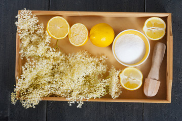 elder flower juice ingredients on wooden tray, black wood table background