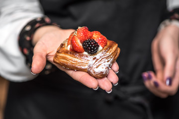 Female hand keep croissant with berries.