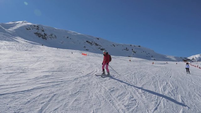Skier Skiing Down The Ski Slope Along The Mountain In Winter Sunny Day