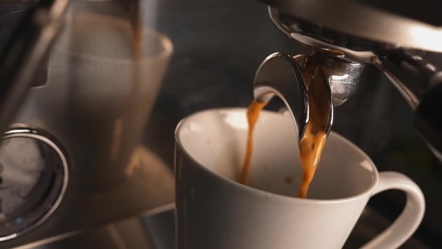 ESPRESSO pours into ceramic CUP from coffee machine &mdash; CLOSE-UP of brewing process in modern cafe