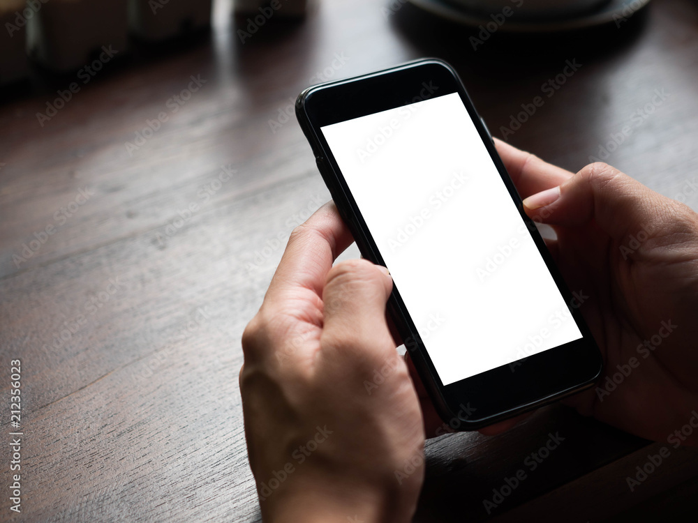 Poster closeup of hands are using a black cell phone on wood table at coffee cafe,concept of smart phone wi