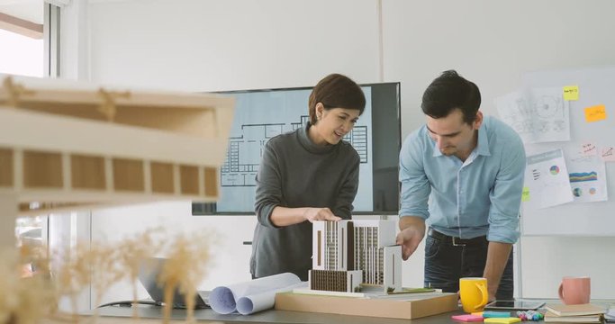 Dolly shot of Confident team of creative architects working together in a architect studio. male architect and colleague constructing an architectural model