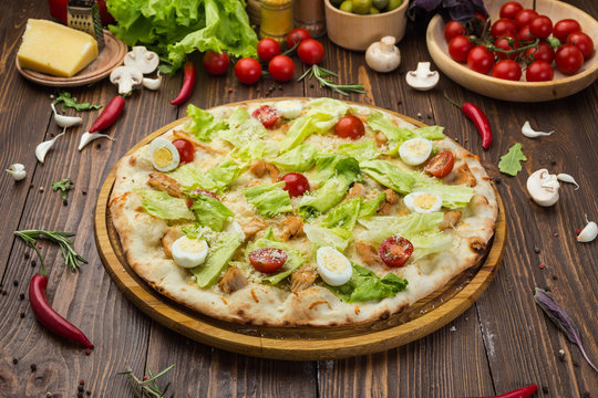 Pizza Caesar with chicken and tomatoes on wooden background