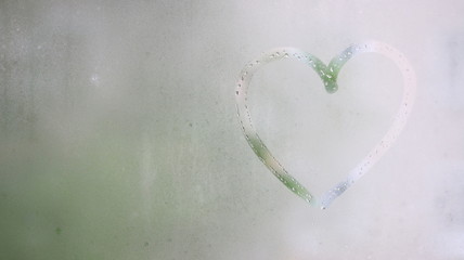 sign heart on wet window with raindrops handwritten