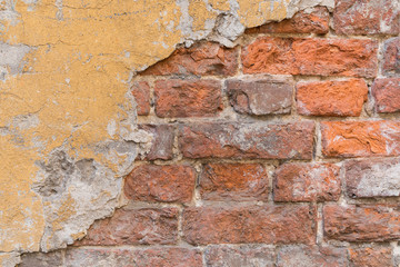 Old damaged brick wall with plaster.