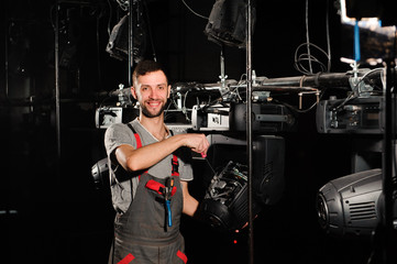 The lighting engineer repairs the light device on stage