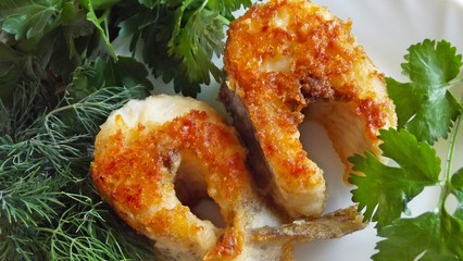 Tasty fried pike with greens on a white plate.