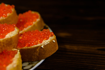 Sandwiches with red caviar on wooden table