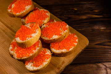 Naklejka na ściany i meble Sandwiches with red caviar on a cutting board