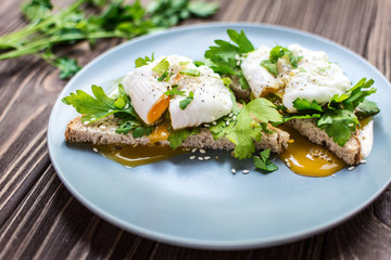 Homemade poached eggs on toast with fresh herbs and pepper