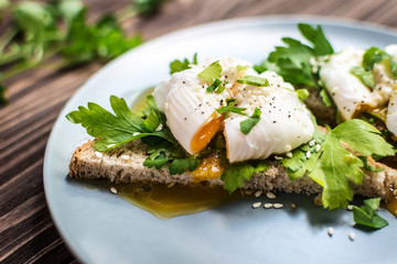 Homemade poached eggs on toast with fresh herbs and pepper