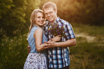 young married couple hugging and looking at camera outdoors