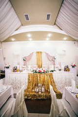 Wedding Banquet hall decorated with flowers, table setting, floral arrangements in the restaurant.