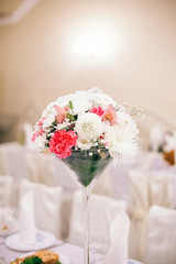 Wedding Banquet hall decorated with flowers, table setting, floral arrangements in the restaurant.
