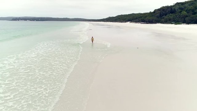 Aerial view of bikini woman walking along in sandy beach