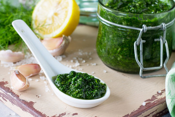 Preserving sauce dill with garlic and olive oil on the kitchen wooden background. Copy space.