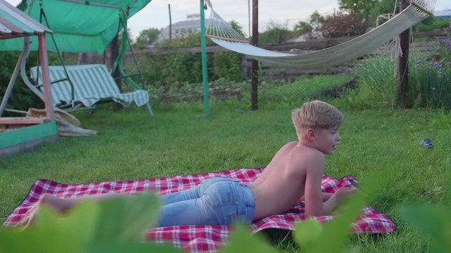 The guy is lying on the lawn on a hot summer day. The child is fun and active to spend their leisure time