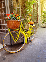 Fototapeta na wymiar Colorful yellow bicycle parked on the old narrow street in Rome, Italy