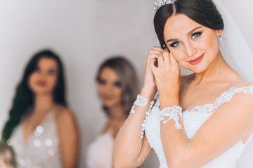 Happy bridesmaid hugging the bride in the bedroom in the morning. Before wedding ceremony. Bride preparing and wait groom. 