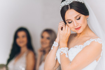 Happy bridesmaid hugging the bride in the bedroom in the morning. Before wedding ceremony. Bride...
