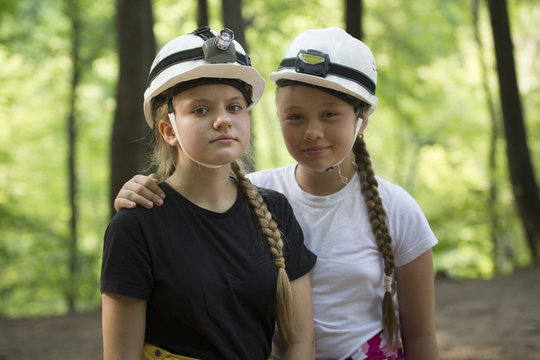 Two teen girls speleologists in helmets in the forest at sunny d
