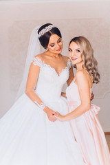 Happy gorgeous brunette bride in white dress having posingwith beautiful bridesmaid