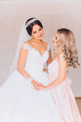 Happy gorgeous brunette bride in white dress having posingwith beautiful bridesmaid