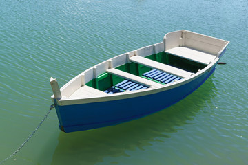 Bright blue rowing boat on the emerald water of the lake