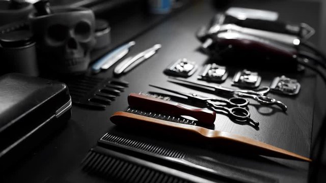 Stylish equipment table with scissors and trimmers and dark scull at the barber shop, making of haircuts, straight razor on the table, shaving salon and barber shop