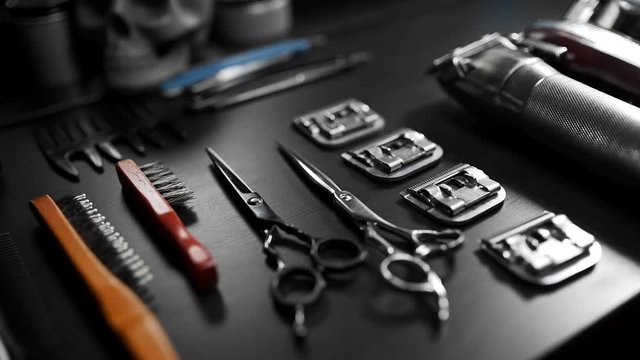 Stylish equipment table with scissors and trimmers and dark scull at the barber shop, making of haircuts, straight razor on the table, shaving salon and barber shop