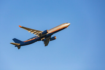 Passenger plane flying in the blue sky in sunlight rays