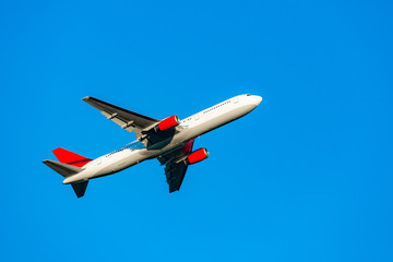 Passenger plane flying in the blue sky in sunlight rays