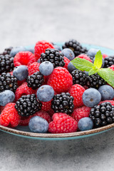 Fresh berry salad on blue dishes. Vintage wooden background.