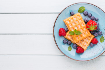 Fresh berry salad on blue dishes. Vintage wooden background.